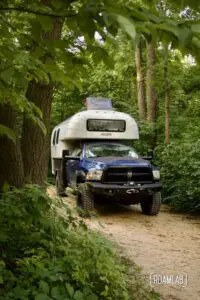 1970 Avion C11 truck camper parked in a forested campsite.