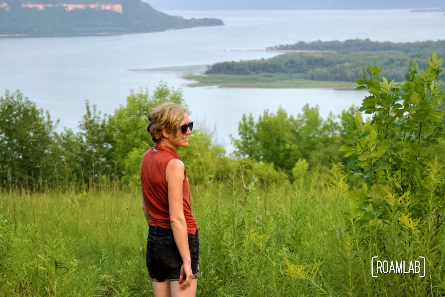 Woman standing in tall grass along a bluff over looking Lake Pepin and the Wisconsin bluffs.