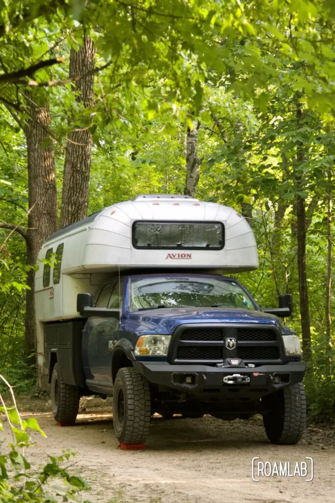 Vintage 1970 Avion C11 truck camper parked in the forest.