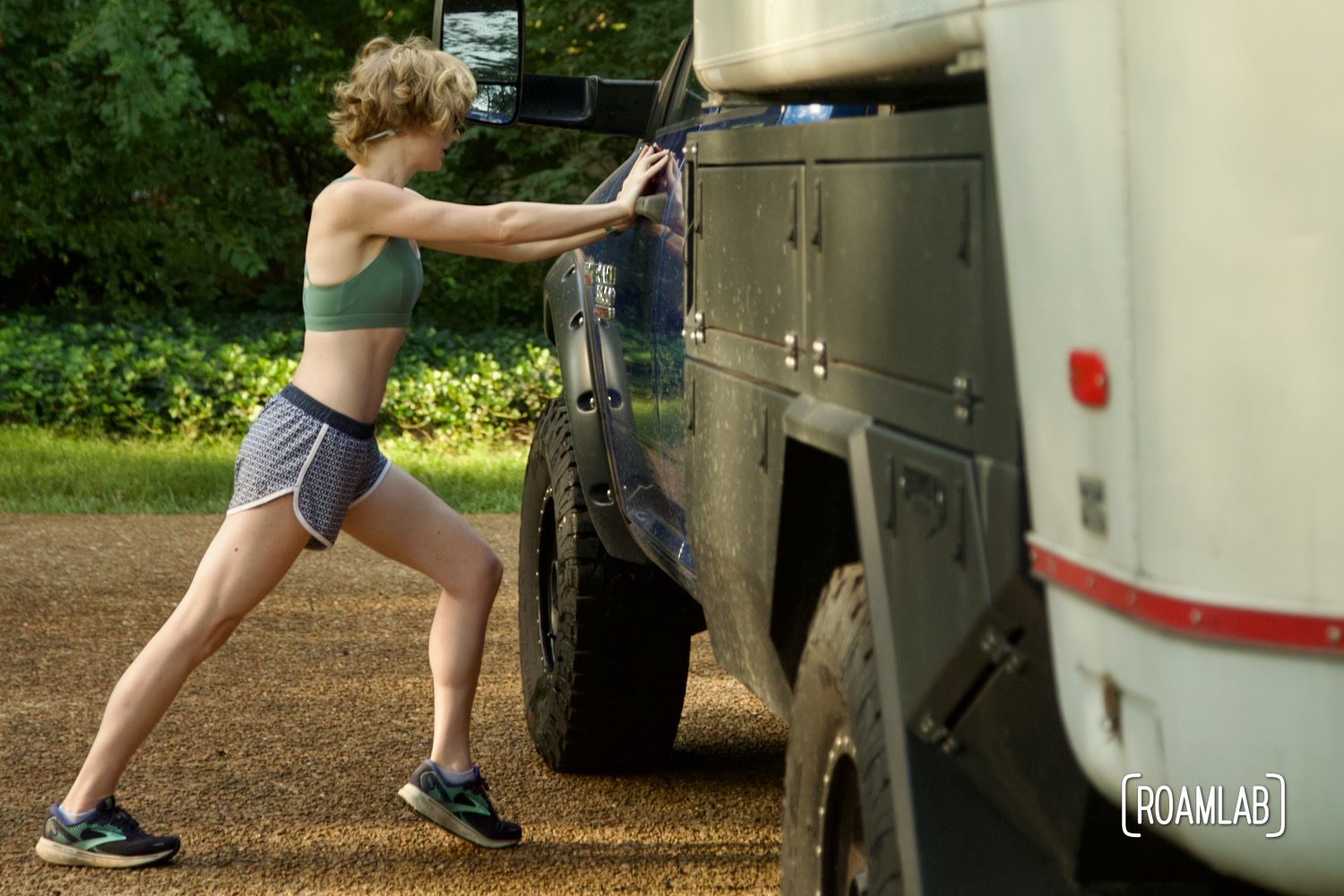 Woman pushing against a truck to stretch her calf muscle.