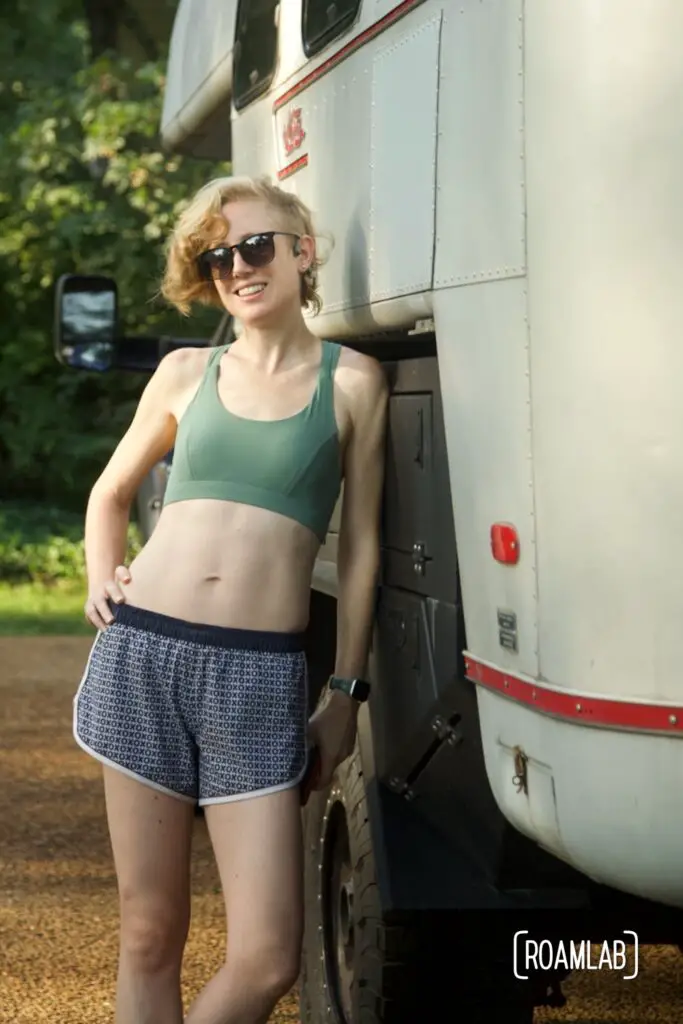 Woman in running gear leaning against a truck camper.