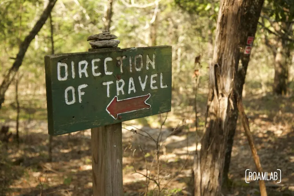 Green sign "Direction of Travel" with arrow pointing left.