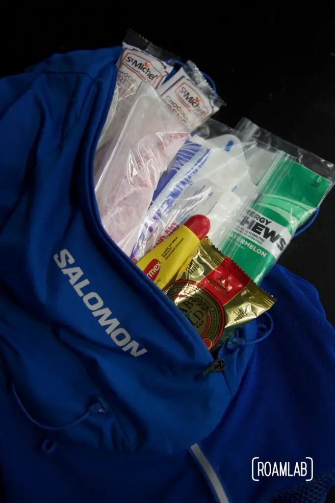 Overlay of back of hydration vest with bandaids, chapstick, and snacks.