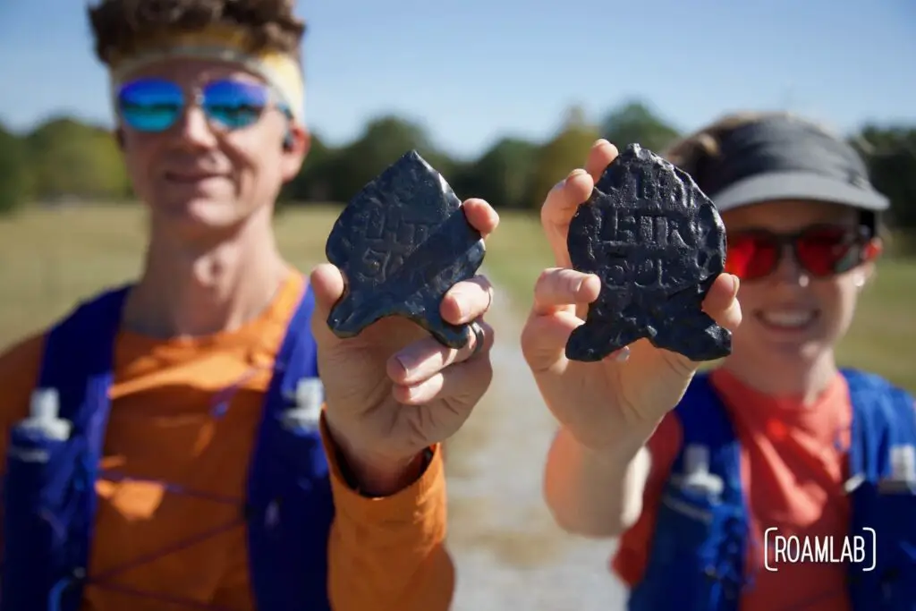 Man and woman holding up ceramic arrowheads.