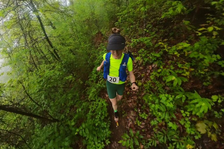 Woman trail running along lush single track.