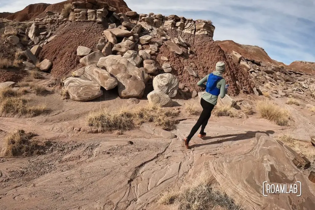 Woman running past a red rock butte on Wilderness Loop in Petrified Forest National Park.