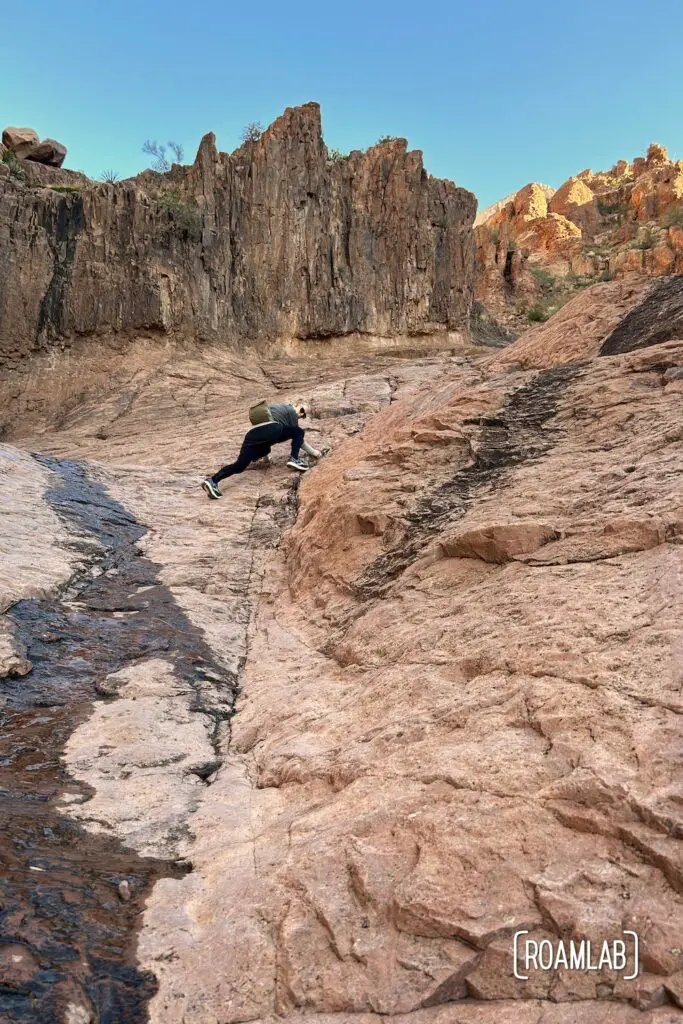 Woman climbing up a rock face on her way up to the Flat Iron in the Superstition Mountains.