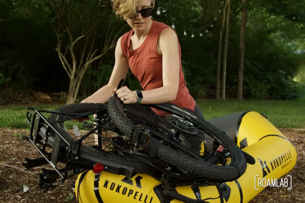 Woman strapping a bicycle to a raft