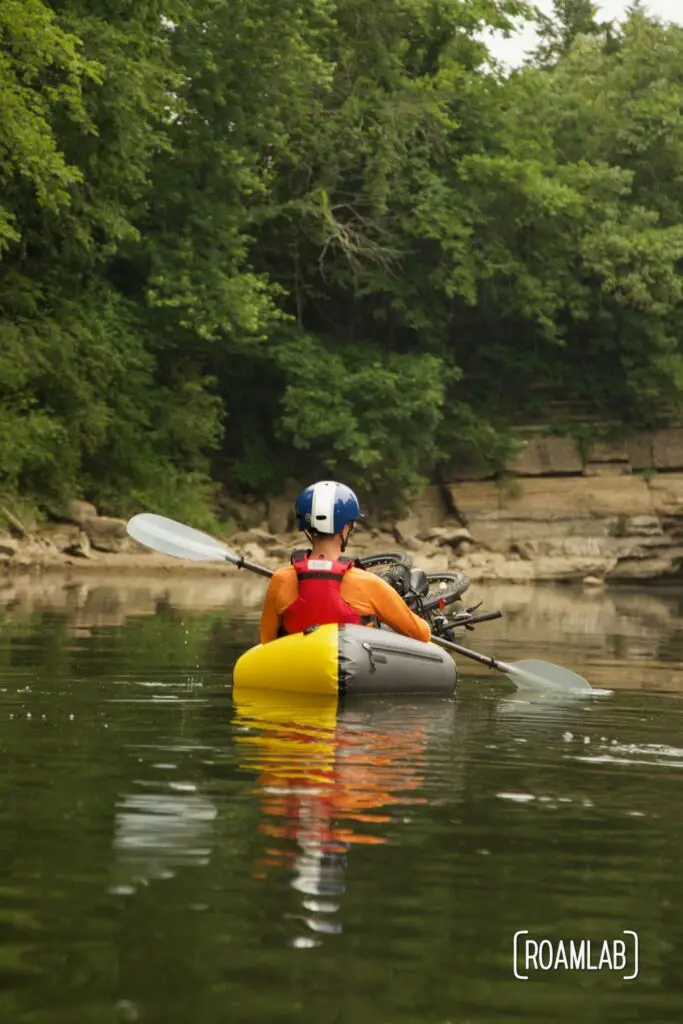 Man in a yellow raft paddling down a river.