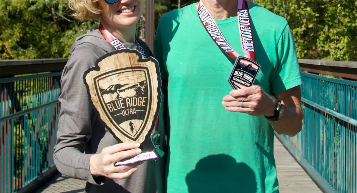 Man and woman holding medals and trophy for "First Woman" from Blue Ridge Ultra 50k.