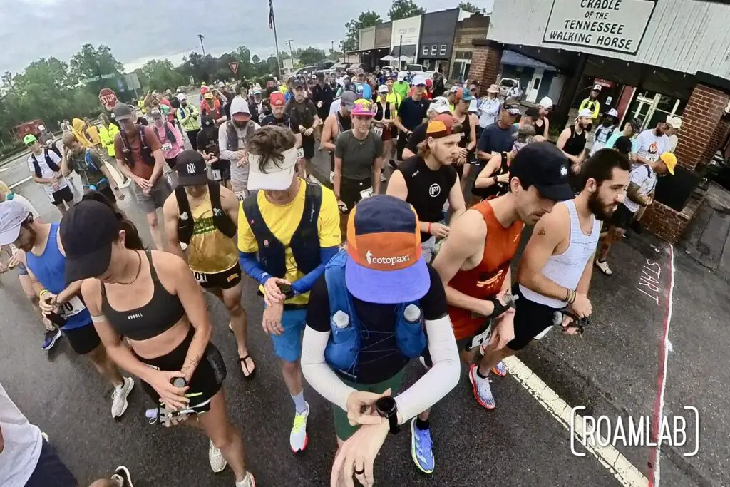 150 people gathered behind a start line, looking down at their watches.