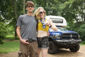 Man and woman standing together with wolf head belt buckles and a medal for the Night Howler 50.