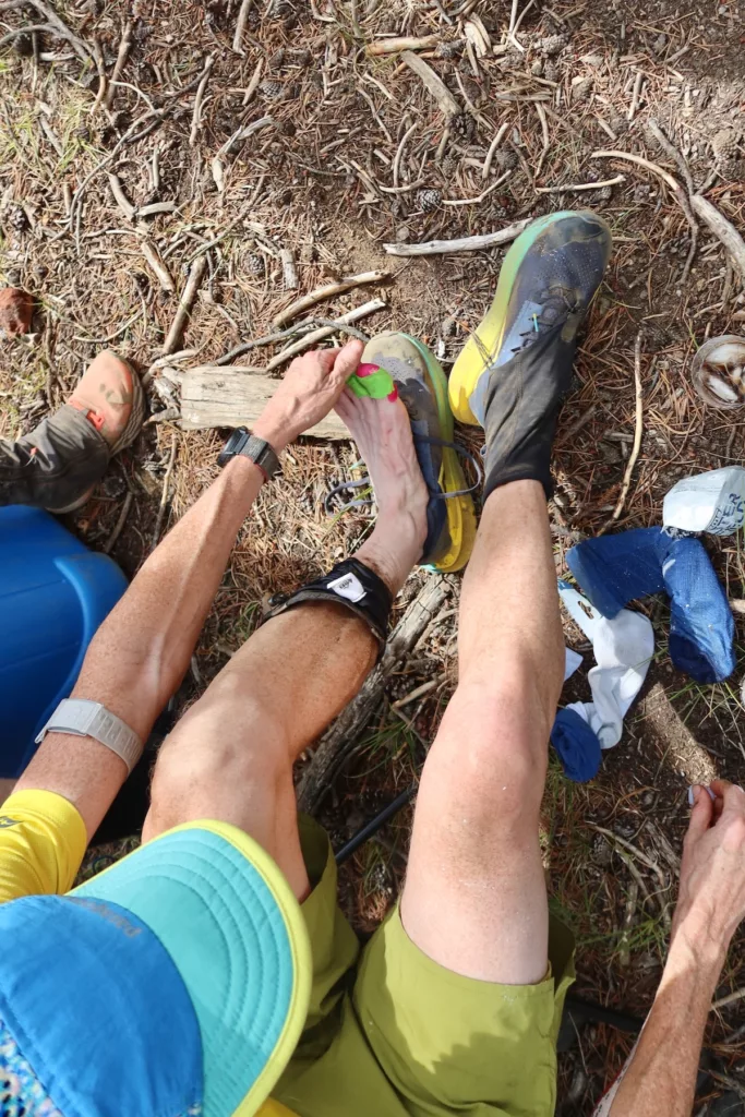 Man caring for his feet in the middle of a trail race.