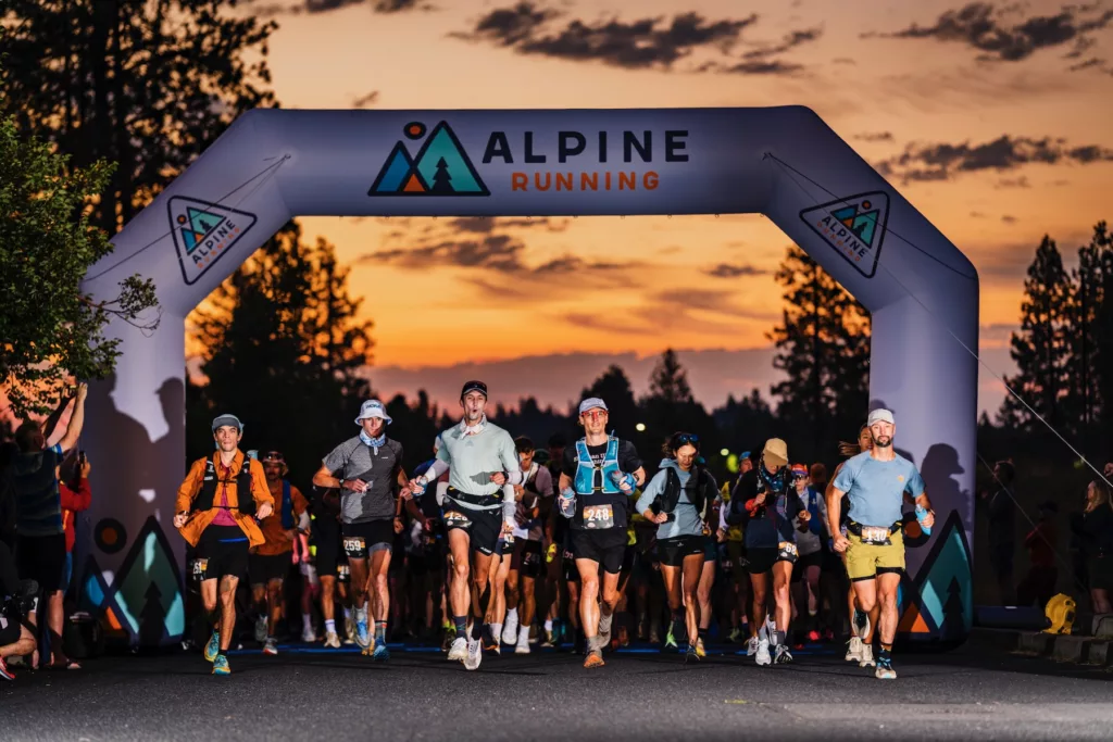 Oregon Cascades 100 runners running across the Alpine Running start line with the sunrise in the background.